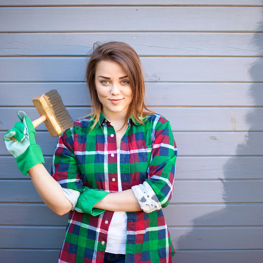 A young smiling woman painting the exterior of her home